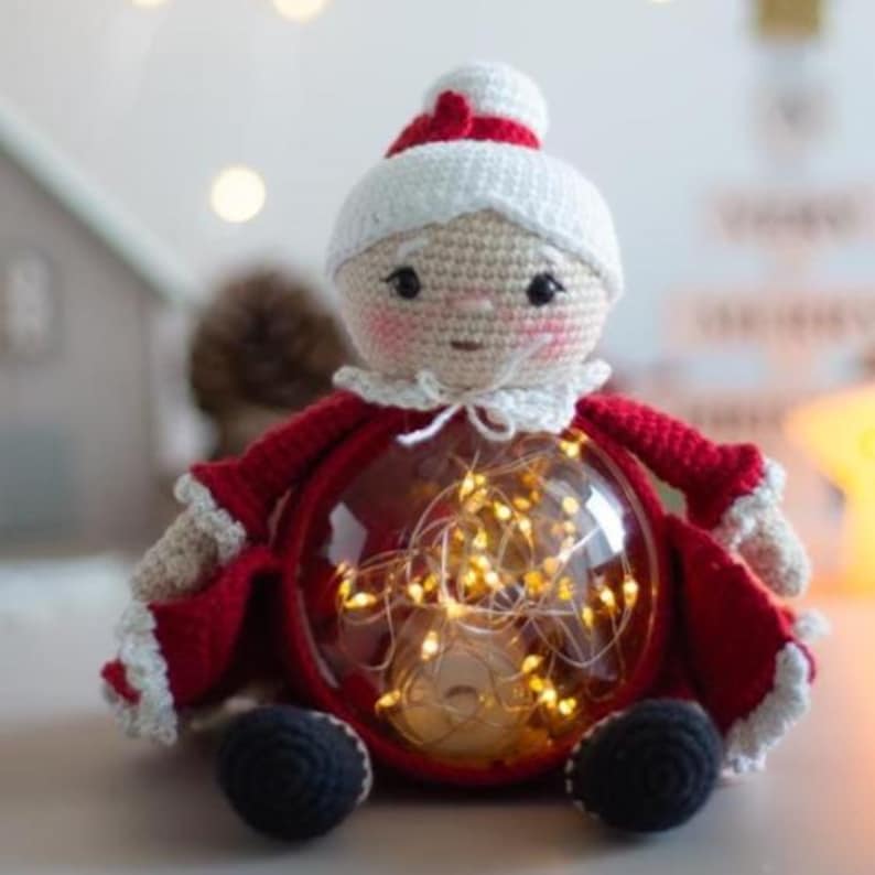 Peut inclure: Une figurine au crochet de Madame Claus avec un corps en forme de globe transparent rempli de guirlandes lumineuses blanc chaud. La figurine a un chapeau blanc avec une bande rouge, une robe rouge et des chaussures noires. Une d&eacute;coration de No&euml;l charmante.