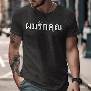 Op de afbeelding: Een donkergrijs t-shirt met de Thaise tekst "พนรักดอน" in wit gedrukt op de voorkant.