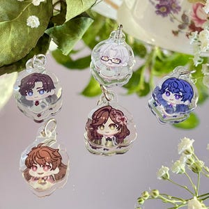 Puede incluir: Cinco colgantes de acrílico transparente con ilustraciones de personajes de dibujos animados. Cada colgante presenta un personaje diferente con cabello y ropa distintivos. Los colgantes cuelgan de aros de metal plateado.