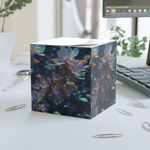 May include: A cube-shaped notepad featuring a colourful underwater scene. The design includes blue, purple and pink coral with orange and yellow fish swimming around.
