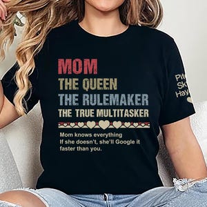 Peut inclure: T-shirt noir avec un graphisme de style vintage qui dit "MOM THE QUEEN THE RULEMAKER THE TRUE MULTITASKER". Le graphisme est en rouge, jaune et bleu. Sous le graphisme, le texte "Mom knows everything. If she doesn't, she'll Google it faster than you."