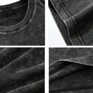 May include: Close-up shots of a dark gray, acid-washed t-shirt. The images highlight the texture and details of the fabric, including the neckline, seams, and overall distressed appearance. The shirt appears to be made of a soft, comfortable material.