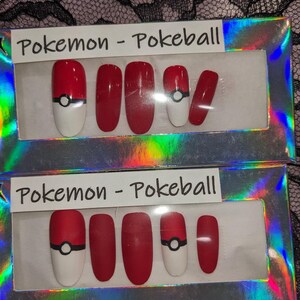 May include: Two sets of fake nails in a clear plastic box. Each set has five nails with a red base and a white tip. One set has a black and white Pokeball design on the thumb nail. The box has the text "Pokemon - Pokeball" on the top.