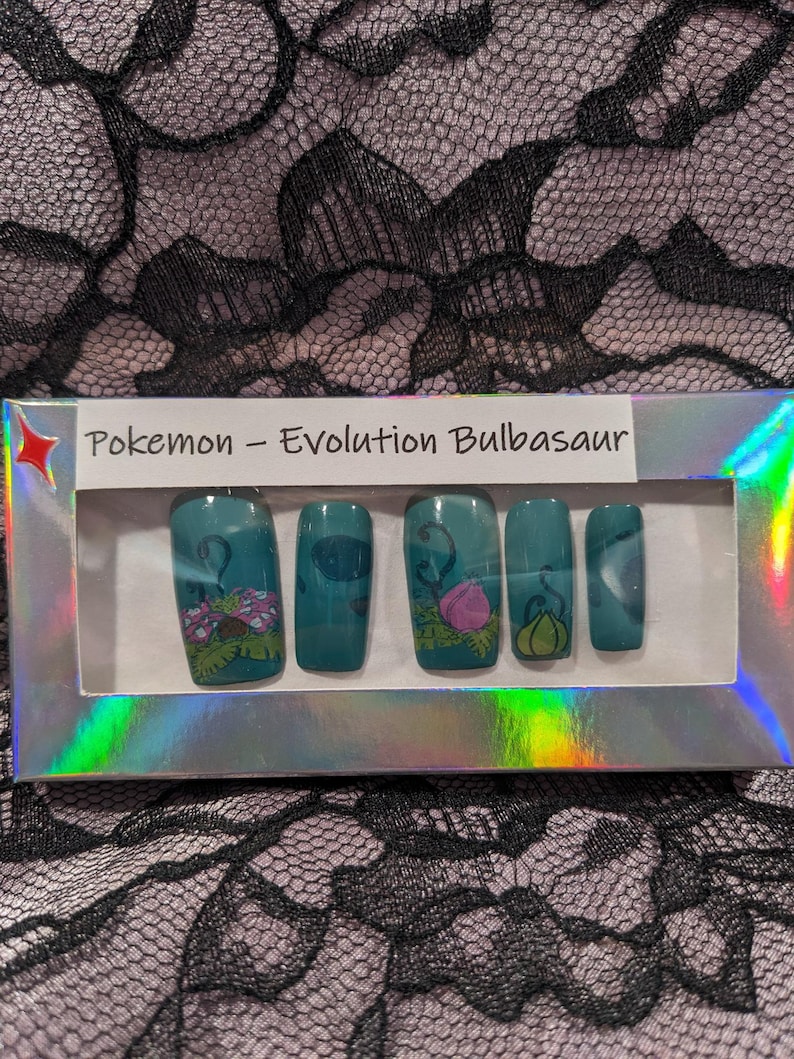 May include: A set of fake nails with a Pokemon theme. The nails are teal green with images of Bulbasaur, Ivysaur, and Venusaur. The box says "Pokemon - Evolution Bulbasaur".