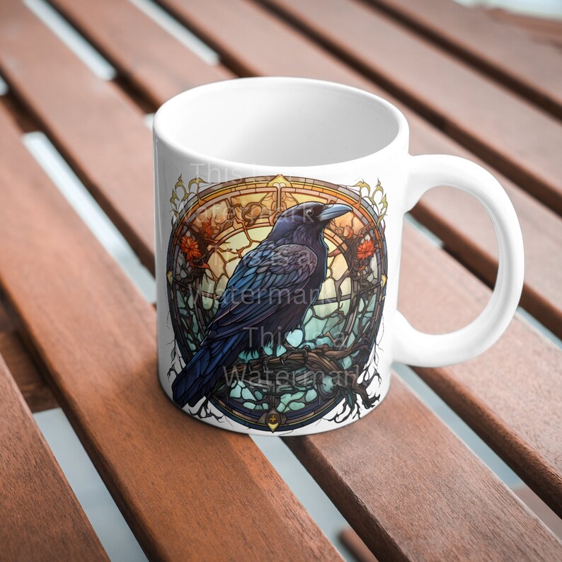 K&ouml;nnte beinhalten: Wei&szlig;e Keramiktasse mit einem bunten Glasmalereidesign, das einen schwarzen Raben auf einem Ast zeigt. Das Design umfasst einen runden Rahmen mit filigranen Details und einem Farbschema in Blau, Gr&uuml;n und Gelb.