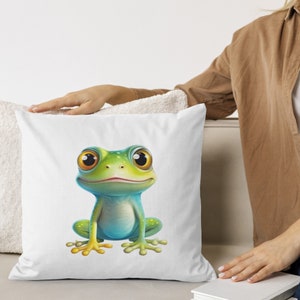 May include: A white throw pillow with a cartoon image of a green and blue frog with large eyes. The frog is sitting on its hind legs with its front legs resting on its belly.