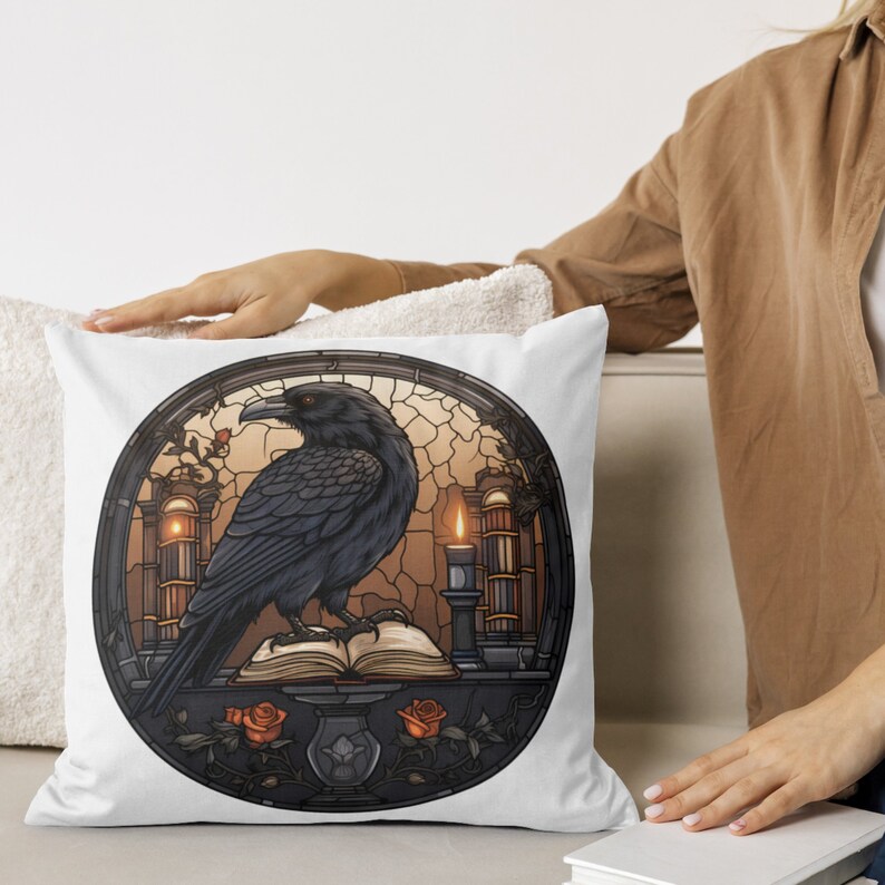 May include: White throw pillow with a stained glass design featuring a black raven perched on an open book with a lit candle and roses.