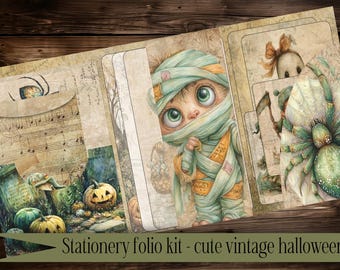 May include: A stationery folio kit with a cute vintage Halloween theme. The design features a mummy-like character with large green eyes, pumpkins, and a spider. The text "Stationery folio kit - cute vintage halloween" is at the bottom.