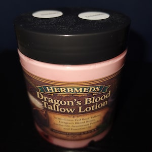 Puede incluir: Un recipiente cilíndrico de loción de sebo Dragon's Blood de Herbmeds con tapa negra. La etiqueta presenta el texto Herbmeds Dragon's Blood Tallow Lotion, with Grass Fed Beef Tallow, Dragon's Blood Resin, Jojoba Oil, Arrowroot Powder and Essential Oil.