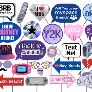 May include: A set of 16 colourful photo booth props with a 2000s theme. The props feature text like "BRB", "Leave Britney Alone", "Back to the 2000s", "I ♥ 00s", "Y2K", "Text Me", "Boy Bands", "Mean Girl", "Crazy in Love", "Will You Be My Myspace Friend?", "OMG", "Girls", "XX", and images of a mobile phone, a CD, a Tamagotchi, a video camera, a heart, a dog, and a pair of sunglasses.
