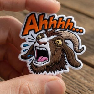 May include: A patch featuring a cartoon goat with an open mouth and the word "Ahhhh..." in orange. The goat is brown and white with yellow eyes and curved horns. Blue water droplets are around the goat's head.