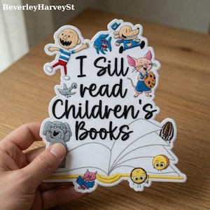 May include: Embroidered patch with the text "I Still Read Children's Books" and illustrations of cartoon characters. The patch features a white background with black lettering and colorful images of a boy, dog, fish, mouse, and other characters.