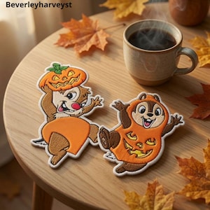 May include: Two embroidered fabric patches featuring cartoon chipmunks in Halloween costumes. One chipmunk holds a jack-o'-lantern on its head, while the other wears a jack-o'-lantern suit. The patches are brown, orange, and white with detailed stitching.