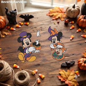 Puede incluir: Dos parches bordados con ratones de dibujos animados disfrazados para Halloween. Un ratón lleva un sombrero de copa y capa morados, sosteniendo una calabaza con un fantasma. El otro lleva un sombrero de bruja y capa naranjas con una bolsa.