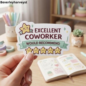 May include: A white rectangular embroidered patch with scalloped edges featuring the text "EXCELLENT COWORKER" in dark red and "WOULD RECOMMEND" in dark red on a light green ribbon, with a smiling yellow star and five yellow star icons.