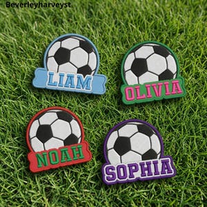 Puede incluir: Cuatro parches circulares con un gráfico de balón de fútbol en blanco y negro. Cada parche tiene una etiqueta rectangular con los nombres Liam en azul claro, Olivia en rosa, Noah en verde y Sophia en morado.