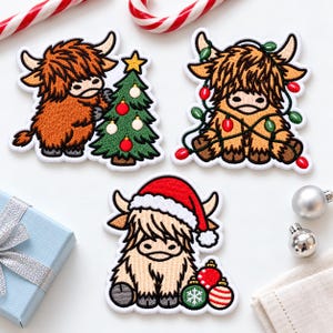 May include: Three embroidered patches featuring fluffy Highland cattle with Christmas themes. One cow decorates a green tree, another is wrapped in colorful string lights, and the third wears a red Santa hat beside ornaments.