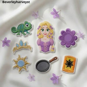 Könnte beinhalten: Eine Sammlung von sieben gestickten Aufnähern mit einer blonden Figur mit lila Blumen im Haar, einem grünen Chamäleon, einem goldenen Diadem mit blauen Edelsteinen, einer lila Blume, einem gelben Sonnenemblem, einer schwarzen Pfanne und einer gelben Laterne.