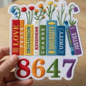 May include: Embroidered patch featuring colorful books with words like "LOVE," "INCLUSION," and "DIVERSITY." The patch also includes the numbers "8647" in vibrant colors, and is topped with embroidered flowers. The patch is on a white background.