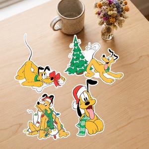 Puede incluir: Cuatro pegatinas de vinilo troqueladas que muestran al personaje de Disney Pluto en varias poses navideñas. Una muestra a Pluto con un lazo rojo, otra con un árbol de Navidad decorado con huesos, una enredada en luces de colores y otra con gorro.