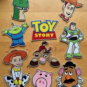 Może przedstawiać: Zestaw haftowanych naszywek przedstawiających postacie z filmu animowanego "Toy Story". Naszywki obejmują Chudego, Buzz'a Astrala, Jessie, Rexa, Hamm'a, Pana Bulwę, Szeryfa i Zielonych Ludzików, wraz z logo "Toy Story".