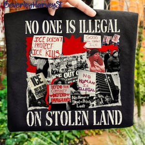 Könnte beinhalten: Schwarzes Grafik-T-Shirt mit dem weißen Text „NO ONE IS ILLEGAL“. Das Design umfasst Bilder von Protesten und Schilder mit Botschaften wie „ICE OUT“ und „DEFEND IMMIGRANTS“. Das T-Shirt zeigt auch die Sätze „ON STOLEN LAND“ und „ICE DOESN'T PROTECT ICE KILLS“.
