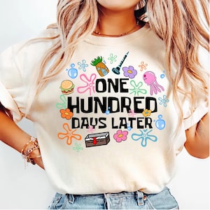 May include: A white t-shirt with a graphic print of cartoon characters and the text "ONE HUNDRED DAYS LATER".