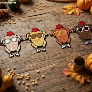 May include: Four embroidered patches shaped like roasted turkeys, each wearing a small red hat and different colored sunglasses. The turkeys are colored light beige, yellow, orange, and brown, featuring detailed stitching and white feet.