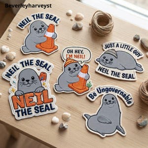May include: Five embroidered patches featuring a grey seal character named Neil. Designs include Neil holding an orange traffic cone, wearing a beanie, and text reading "Neil the Seal," "Oh Hey, I'm Neil!," "Just a Little Guy," and "Be Ungovernable."
