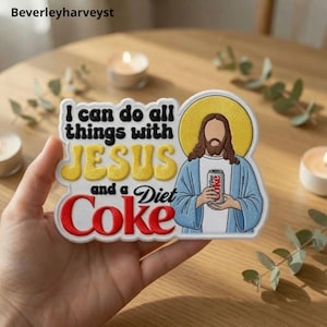 May include: A rectangular embroidered patch featuring a figure with long brown hair and a blue robe, holding a silver soda can. The text reads: I can do all things with JESUS and a Diet Coke. The design includes a yellow halo behind the figure.