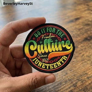 以下が含まれることがあります： 「Do It For The Culture」と「Juneteenth Since 1865」の文字が入った丸い刺繍パッチ。パッチは黒い背景に緑、黄色、オレンジ、赤の文字とアクセントが施されています。