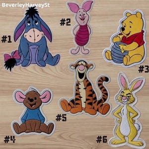 Peut inclure: Écussons brodés représentant des personnages d'une série pour enfants. Comprend un âne bleu, un cochon rose, un ours jaune avec une chemise rouge, un kangourou marron, un tigre orange et un lapin jaune. Chaque écusson est numéroté.