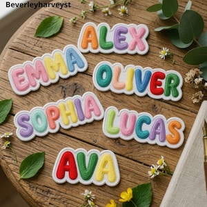 May include: Five embroidered name patches featuring the names Alex, Emma, Oliver, Sophia, Lucas, and Ava in colorful, puffy, bubble-style lettering with white borders. Each letter is a different vibrant color, including red, orange, yellow, green, blue, and purple.