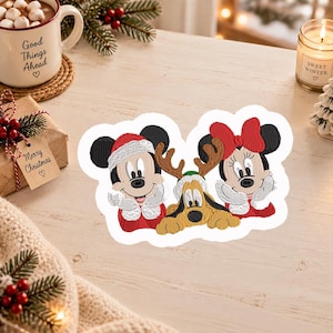 Pode incluir: Um emblema bordado apresentando o Mickey Mouse com um gorro de Pai Natal, a Minnie Mouse com um laço vermelho e o Pluto com hastes de rena. As personagens são representadas num estilo festivo com fios de cores vermelha, branca, preta e castanha.