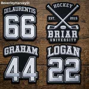 May include: Four black and white embroidered patches. One patch reads "DILAUENTIS 66", another says "GRAHAM 44", and a third says "LOGAN 22". The fourth patch has crossed hockey sticks and reads "HOCKEY EST. 2015 BRIAR UNIVERSITY".