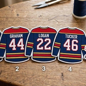 May include: Four die-cut stickers shaped like hockey jerseys in navy blue, red, and yellow, each featuring a unique name and number. A fifth sticker displays the text "show me & I'll show you OFF CAMPUS" with hockey sticks and a small pink heart.