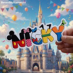 May include: A colourful embroidered patch spelling "Mickey", with each letter themed after a different Disney character. The patch has a white border with black, red, yellow, pink, and blue details. The background shows a castle, balloons, and festive decorations.