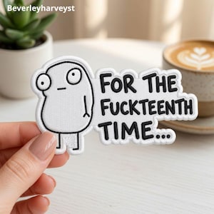 Könnte beinhalten: Ein weißer gestickter Aufnäher mit einer Cartoon-Figur mit großen Augen und neutralem Ausdruck, begleitet von dem schwarzen gestickten Text "FOR THE FUCKTEENTH TIME..." in einer fetten serifenlosen Schrift, mit weißem Rand.