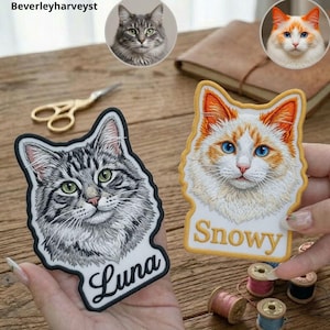 Puede incluir: Dos parches bordados con retratos detallados de gatos. Uno muestra un gato atigrado gris con ojos verdes y el nombre Luna en negro. El otro presenta un gato blanco y naranja con ojos azules y el nombre Snowy escrito en letras de color dorado.