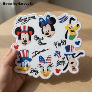 Könnte beinhalten: Weißer, gestickter Aufnäher mit Micky Maus, Minnie Maus, Donald Duck, Daisy Duck, Pluto und Goofy. Der Aufnäher enthält den Text "Mickey Mouse", "Minnie Mouse", "Donald", "Daisy", "Pluto" und "Goofy". Die Charaktere tragen patriotische Accessoires.
