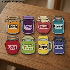 May include: Eight colourful jar-shaped patches arranged in two rows. The jars feature labels with the words faith, Pray, Blessed, Eternal, Love, Gratitude & Grace, Hope, and Believe. Each jar has a distinct colour including orange, purple, red, teal, and yellow.