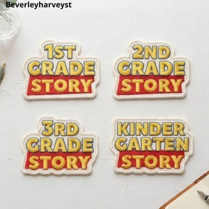 May include: Four embroidered patches with white borders, each featuring yellow text on a red background. The patches read 1ST GRADE STORY, 2ND GRADE STORY, 3RD GRADE STORY, and KINDERGARTEN STORY, styled with bold, block lettering and a distinct layered design.