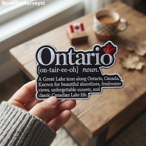 May include: A black embroidered patch with white text that reads Ontario [on-tair-ee-oh] noun. A Great Lake icon along Ontario, Canada, Known for beautiful shorelines, freshwater views, unforgettable sunsets, and classic Canadian Lake life. A red maple leaf icon is at the top right.