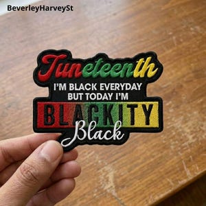 Puede incluir: Un parche negro con la palabra "Juneteenth" en letras rojas, verdes y amarillas. El parche también presenta el texto "I'M BLACK EVERYDAY BUT TODAY I'M BLACKITY Black" en un diseño colorido.