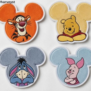 May include: Four embroidered patches shaped like Mickey Mouse ears featuring Tigger in orange, Winnie the Pooh in yellow, Eeyore in gray, and Piglet in light blue. Each character is depicted from the chest up with a white border. Text reads Beverleyharveyst.