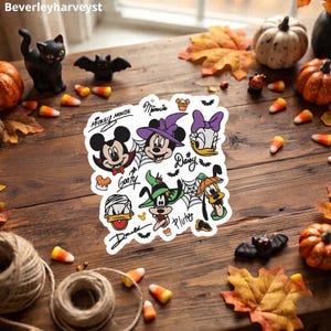 Könnte beinhalten: Ein quadratischer Aufkleber mit Disney-Figuren in Halloween-Kostümen, darunter Mickey Mouse als Vampir, Minnie Mouse als Hexe, Daisy Duck, Donald Duck als Mumie, Goofy als Hexe und Pluto mit einem Kürbis, verziert mit Spinnenweben und Fledermäusen.