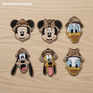 Può includere: Sei toppe ricamate raffiguranti teste di personaggi dei cartoni animati che indossano cappelli da safari con dettagli leopardati. I personaggi includono Topolino, Minnie, Paperino, Pippo, Pluto e Paperina, in fili beige, neri e bianchi.