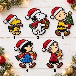 May include: Five embroidered patches featuring Peanuts characters in Christmas attire. Woodstock holds a candy cane, Snoopy carries a gift, Charlie Brown holds a tree, Lucy carries a gift, and Linus holds a gingerbread man. Each is numbered.