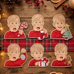 Puede incluir: Seis adornos decorativos planos y troquelados que muestran a un niño de dibujos animados con cabello rubio y un suéter rojo. Cada adorno presenta una pose distinta: sosteniendo un bastón de caramelo, un calcetín, un árbol, una bola, un regalo o galleta.