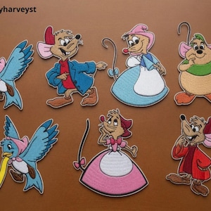 Puede incluir: Una colección de siete parches bordados con personajes de dibujos animados, incluyendo dos pájaros azules, tres ratones con ropa y dos ratones con vestidos de faldas rosas y azules. El texto Beverleyharveyst es visible en la esquina superior izquierda.